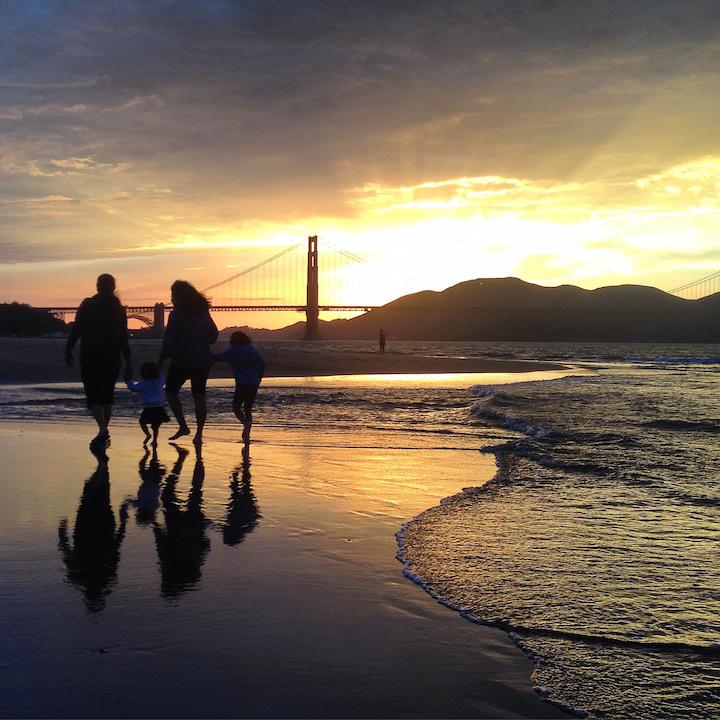 A family walking on Crissy Field beach at sunset with the Golden Gate Bridge in the background. Photo by Scott Sawyer.