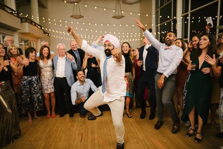 Man dances at a wedding with a large group of people.