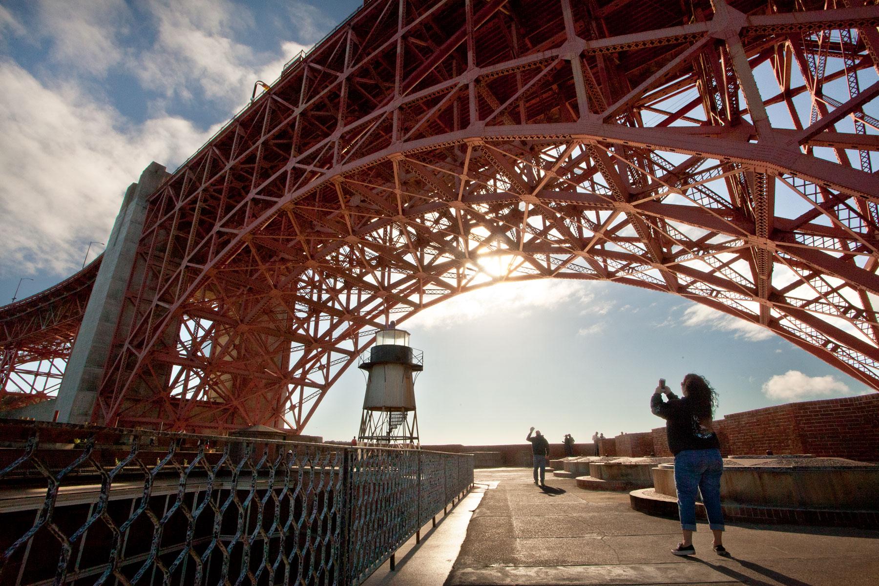 A woman taking a photo of the Golden Gate Bridge from Fort Point. Photo by Scott Sawyer.