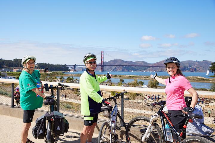 Three bicyclists enjoy the view of the Golden Gate Bridge from a Presidio Tunnel Tops overlook. Photo by Rachel Styer.