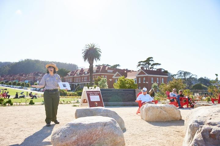 A female park ranger speaks to a group of visitors.