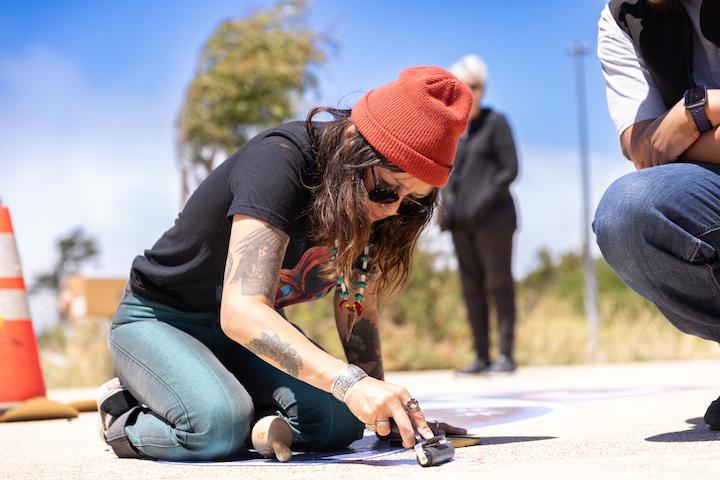 Image of Felicia Gabalon installing murals at the Outpost.