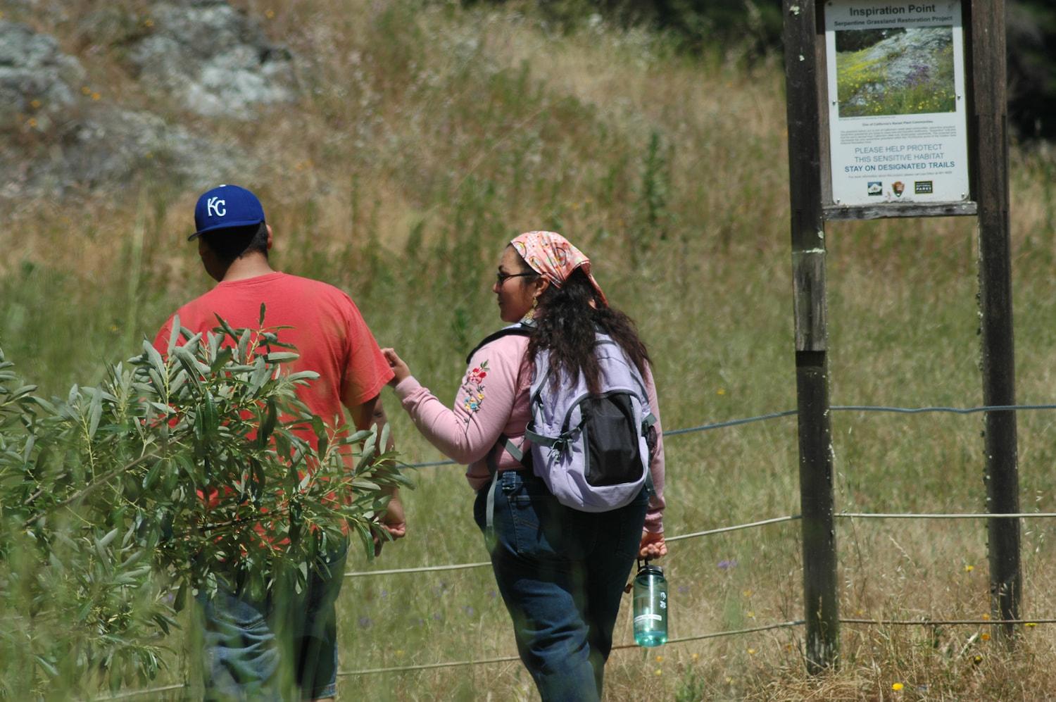 Two people walking through the native grasslands on the Ecology Trail.