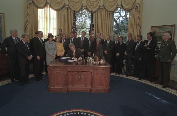 President Bill Clinton signing bill in Oval Office. Image courtesy William J. Clinton Presidential Library.