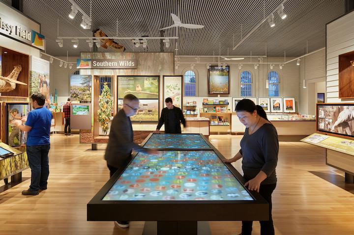 Interior of Presidio Visitor Center with people looking at an interactive digital table. Photo by Mathew Millman.