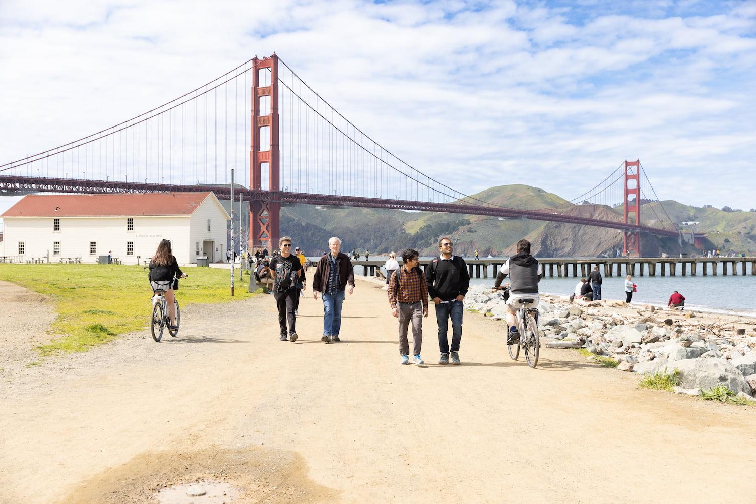A group of people walking or bike riding on Golden Gate Promenade near the Warming Hut.