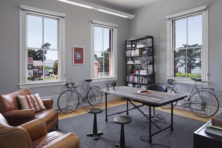 image of an office space with a desk, chair and bike on the wall.
