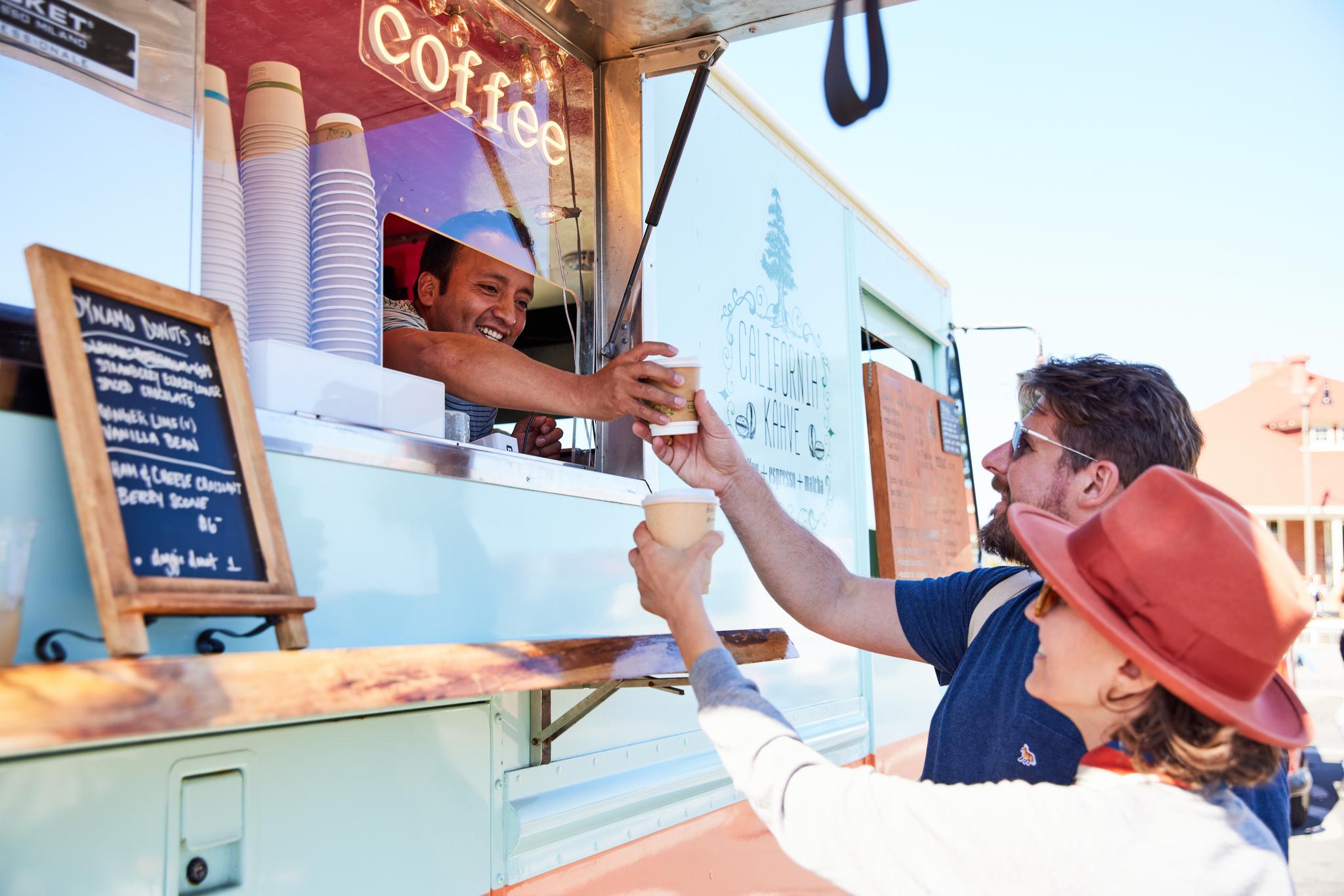 man and woman being served coffee from a coffee truck